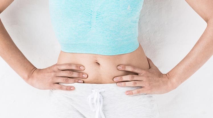 Frau berührt die Haut ihres Bauches